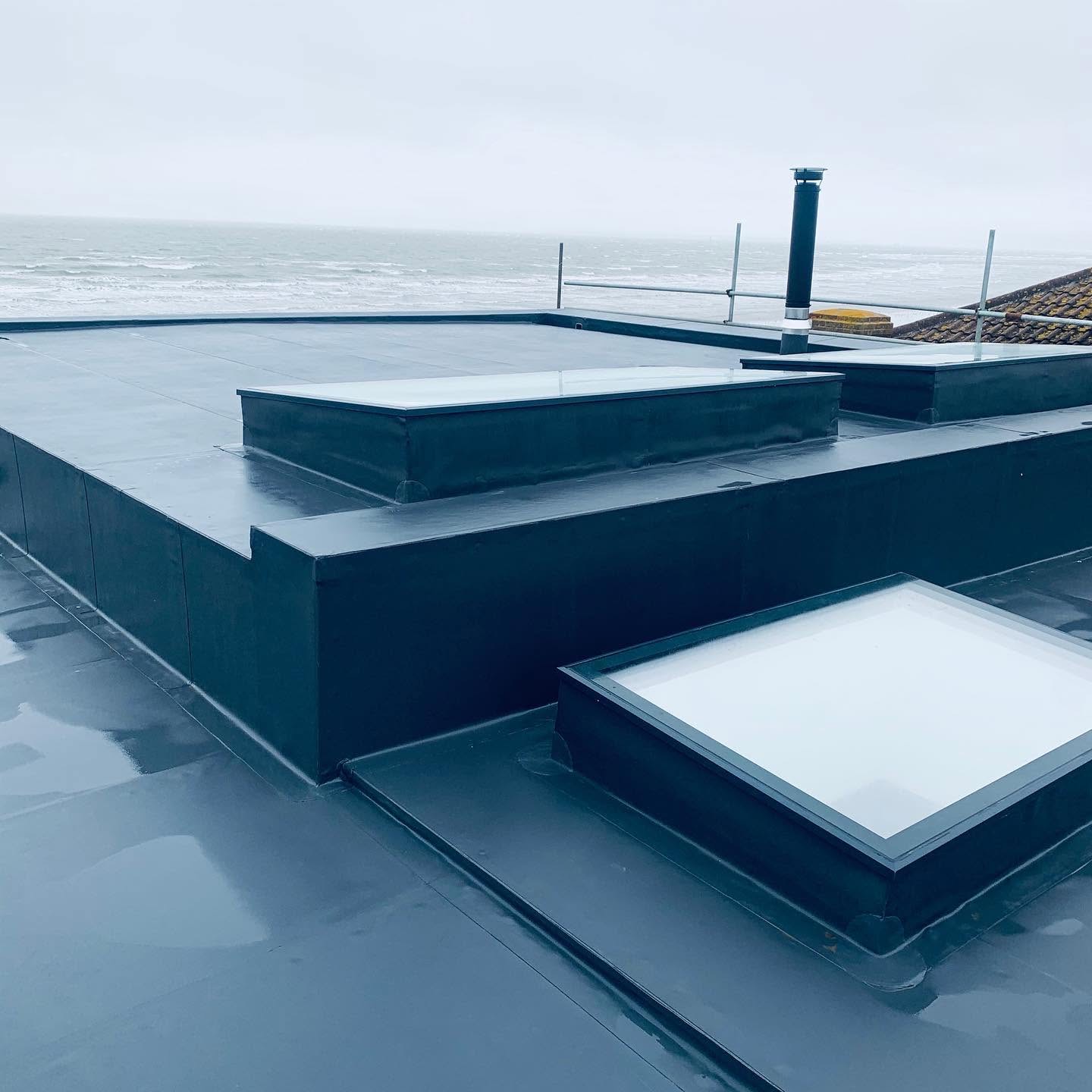Single-ply flat roof with skylights completed by SRB, sea in the background.