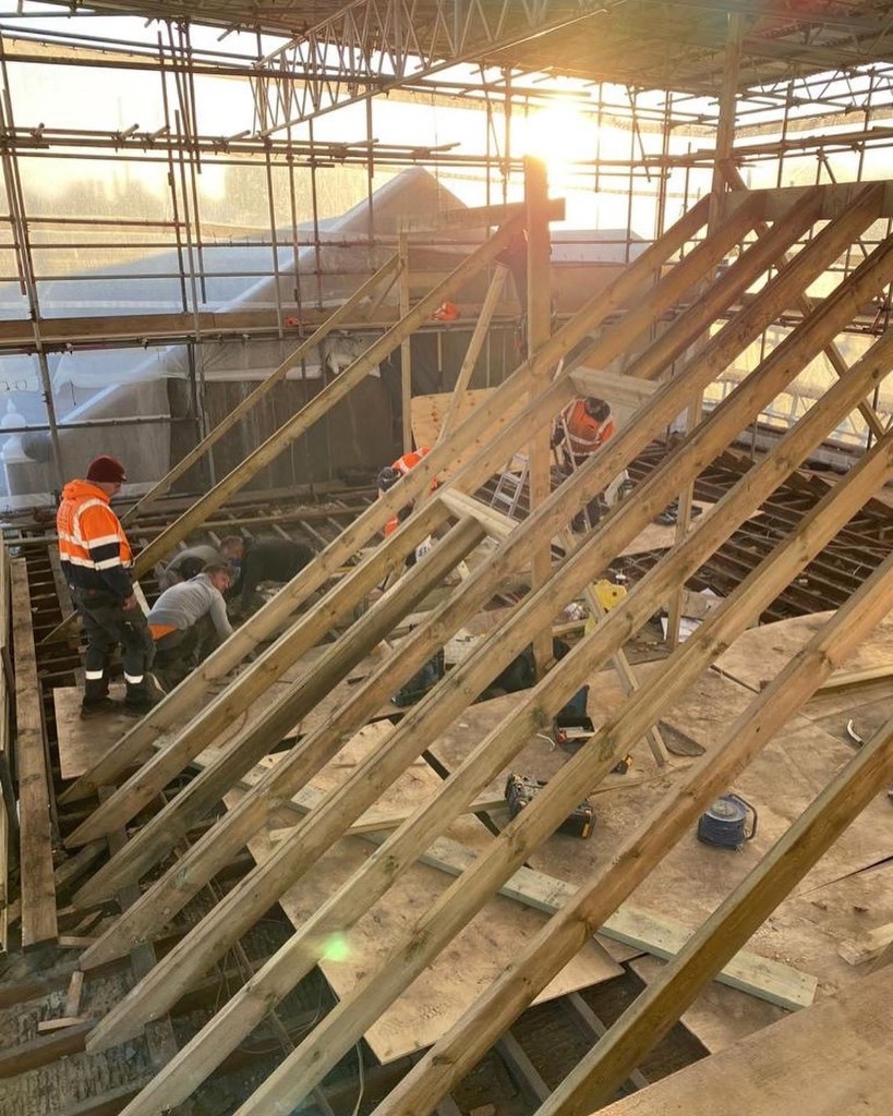 SRB Services crew rebuilding a roof structure under an enclosed scaffold, timber rafters going in.