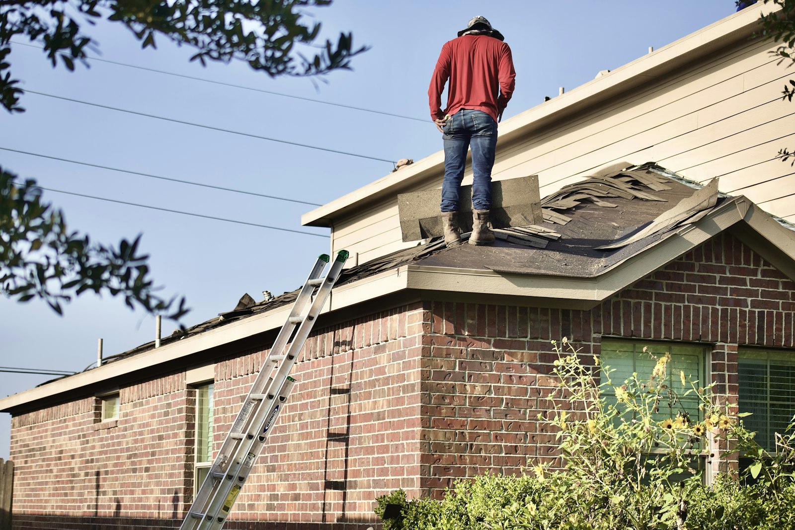 Roofer inspecting the roof of a brick house.