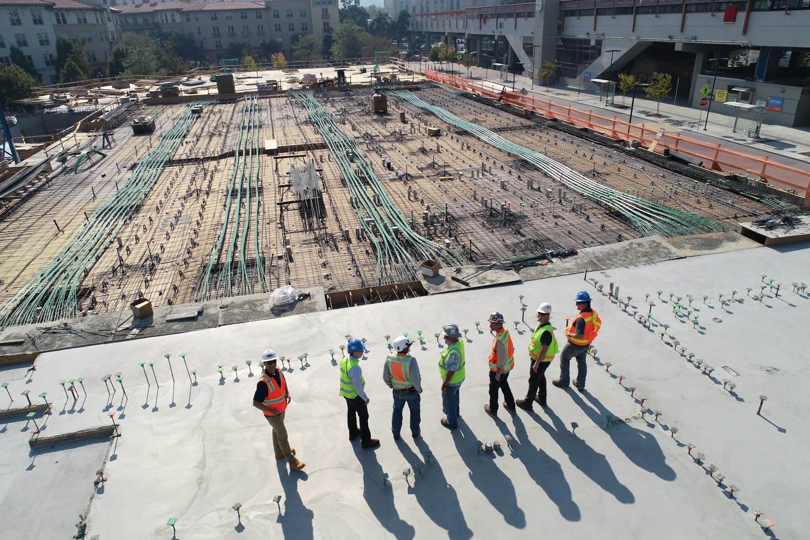 Construction crew in hi-vis and hard hats walking a large live site.