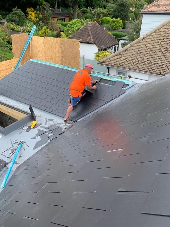 SRB roofer fixing new slate tiles on a pitched roof.